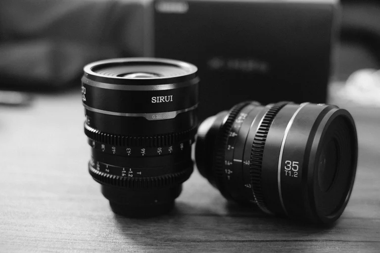 Black and white shot of two Sirui Nightwalker lenses on a table. The two lenses pictured are the 24mm and 35mm.