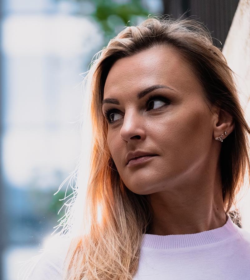 Backlit street portrait of Rina taken on the streets of the City of London. She looks off-camera into the distance.