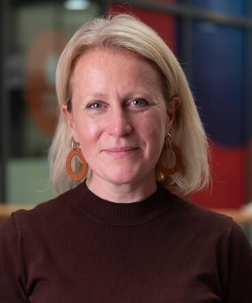 Corporate headshot of a female executive from London. She portrays confidence and warmth and looks straight to camera.